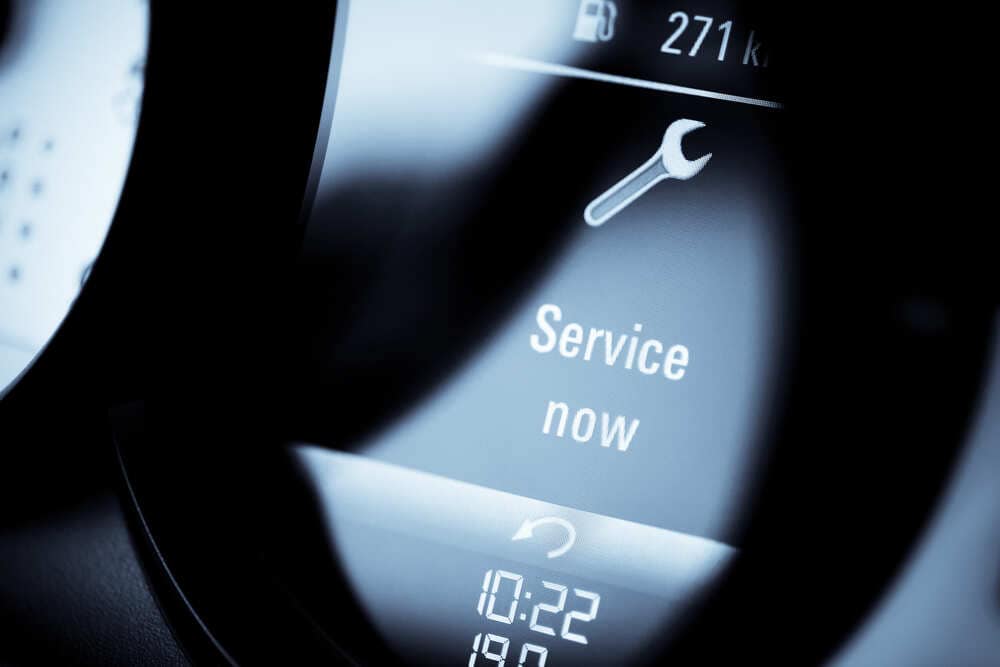 Close-up view of a car dashboard showing a yellow wrench icon and the alert message "Service now," indicating the need for immediate vehicle maintenance. Part of the fuel gauge and an odometer reading of 271 kilometers are visible, signaling it's time to visit a trusted auto repair shop in Clarke County.