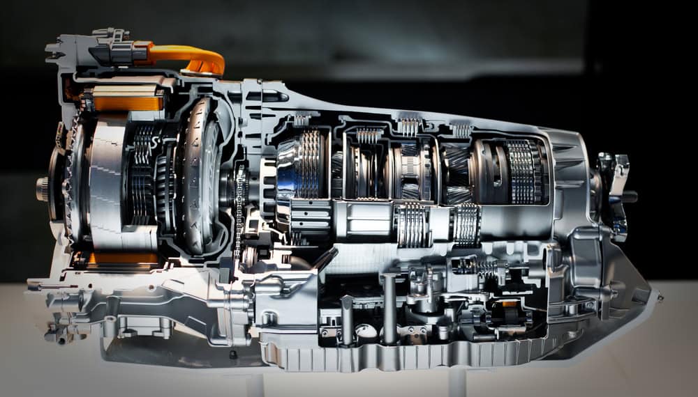 A close-up, cross-sectional view of a complex automotive transmission system, showcasing gears, shafts, and other internal components. The machinery is metallic and highly detailed, mounted on a display stand against a dark background—ideal for anyone interested in Transmission Repair Clarke County.