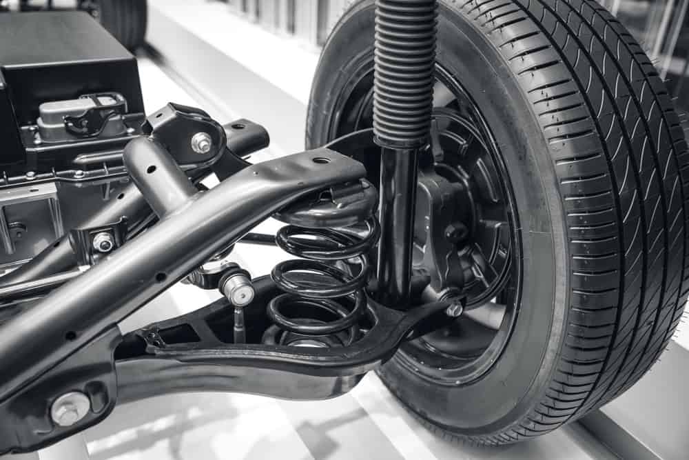 Close-up view of a car's suspension system, showcasing the coil spring, shock absorber, and various structural components attached to the rear wheel. The image highlights the detailed mechanics of the vehicle's suspension setup, ideal for those seeking expert auto repair in Clarke County.