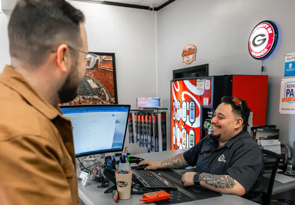 A shop worker and customer speaking in front of a monitor.